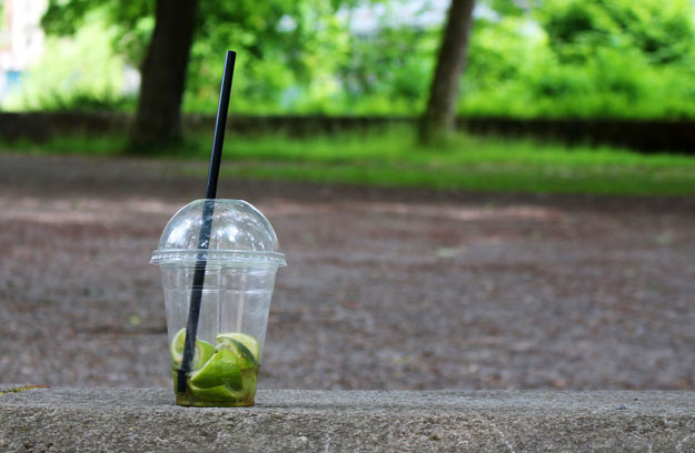 Empty plastic smoothie cup sitting on pavement in park