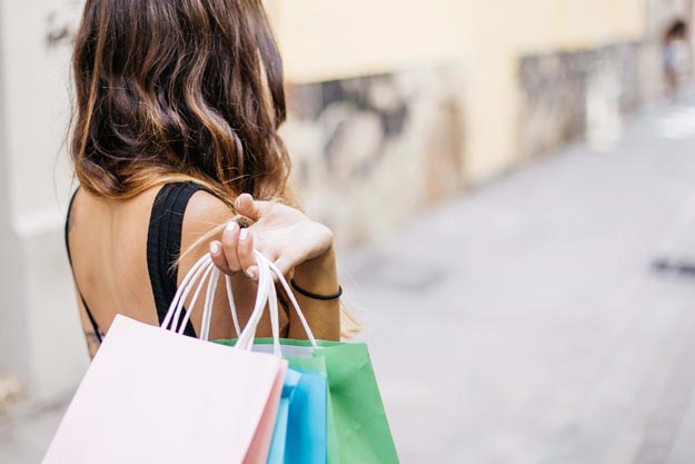 Woman holding three shopping bags over her shoulder