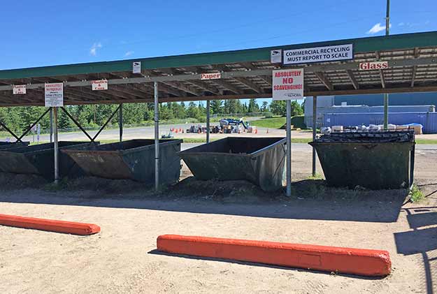 Multiple recycling dumpsters under awning